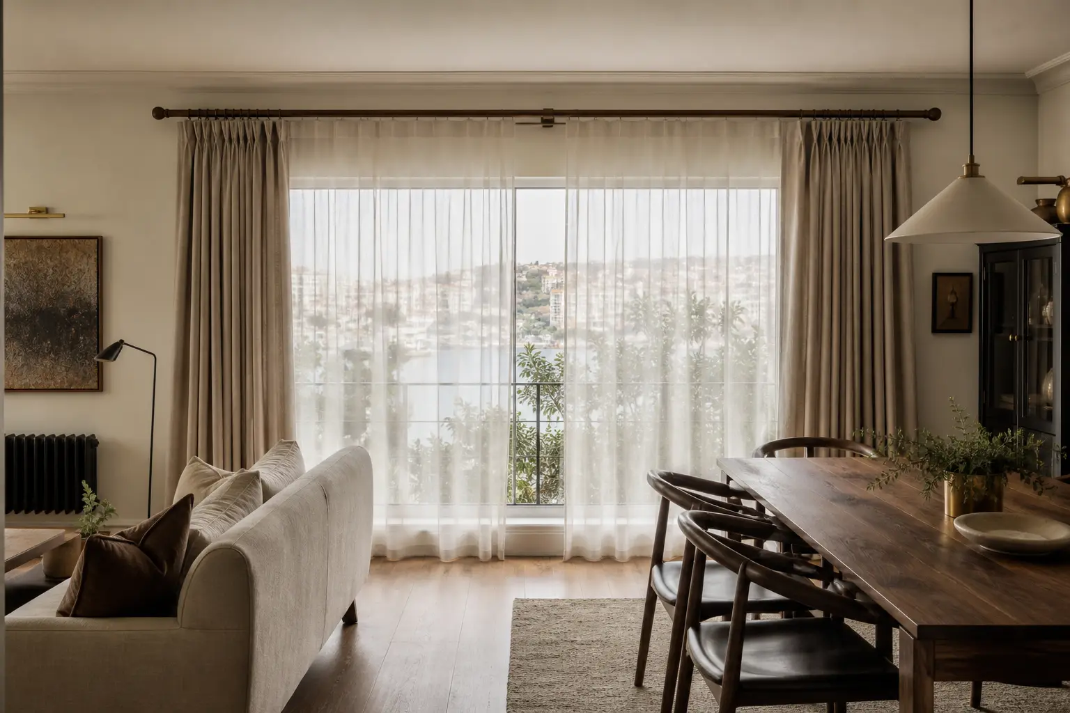 Salon ve yemek alanındaki geniş pencerede kırık beyaz tüller ve taş rengi fon perdeler